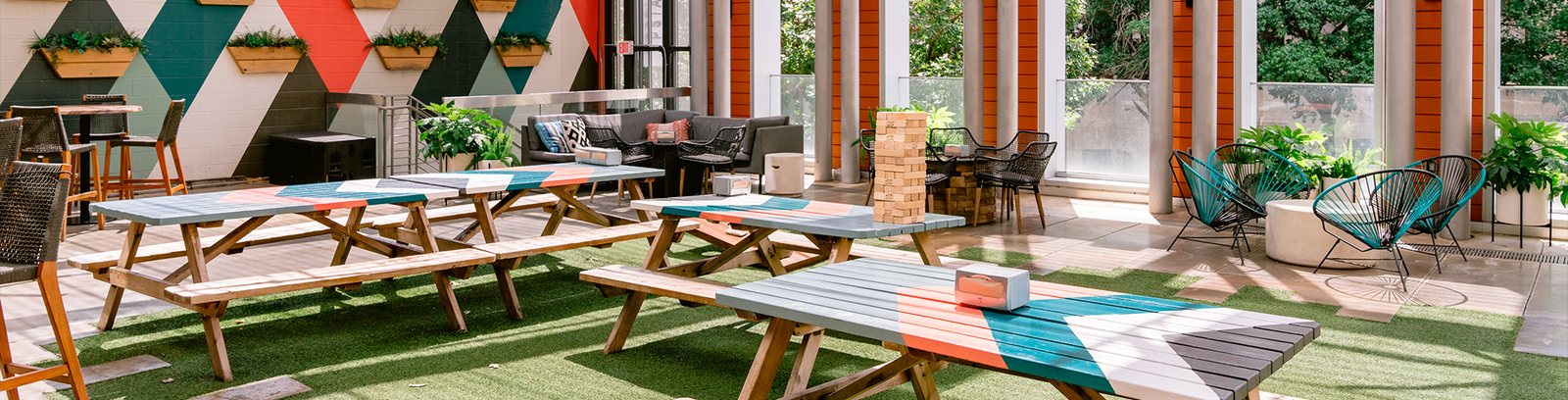 The astroturf rooftop deck at Upstairs at Caroline with picnic tables and lawn games