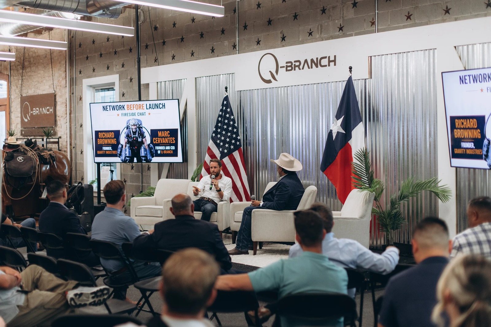 A panel session on the stage at Q Branch with the audience seated